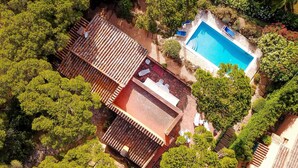 Vista aérea de una propiedad con piscina rodeada de exuberante vegetación y una estructura de techo de tejas.