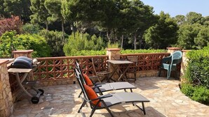 An outdoor patio with stone flooring, a grill, and a seating area with chairs and a table. - Casa Pollo (Begur) (Begur)