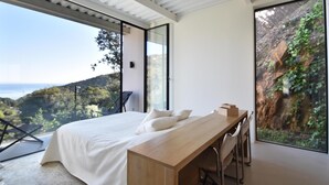 A bedroom with a large bed, a wooden desk, and a view of a mountainous landscape. - Villa Energias Serenas (Begur, Sa Riera) (Begur)
