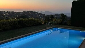 A swimming pool with a clear view of a distant cityscape at sunset. - Villa Amaya (Begur, Costa Brava) (Begur)