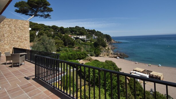 A balcony with a stone wall, outdoor furniture, and a view of a beach and ocean. - Apartament Catalonia (Begur, Sa Riera) (Begur)