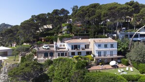 A hillside residential area with multiple houses, including a white building with a balcony and a stone building with a tiled roof. - Apartament Catalonia (Begur, Sa Riera) (Begur)
