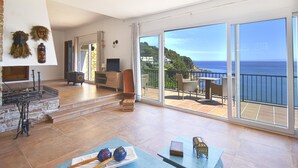 A spacious living room with a large sliding glass door leading to a balcony with a sea view. - Apartament Catalonia (Begur, Sa Riera) (Begur)