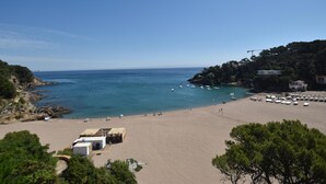 A beach with clear blue water, a sandy shore, and a few buildings in the background. - Apartament Catalonia (Begur, Sa Riera) (Begur)