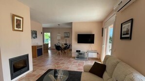 A living room with a fireplace, a sofa, a glass coffee table, and a TV. - Casa Bosc (Begur) (Begur)