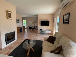 A living room with a fireplace, a sofa, a glass coffee table, and a TV.