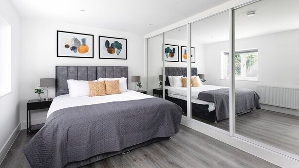 Un dormitorio moderno con una cama grande, un espejo y obras de arte en la pared.