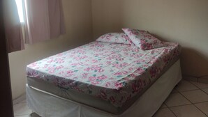 Ein Schlafzimmer mit Bett, Deckenventilator, Klimaanlage und einem Fenster mit Vorhängen.
