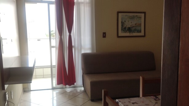 Ein Wohnzimmer mit einer Couch, einem Esstisch, einem Deckenventilator und einem fenster mit Vorhängen.