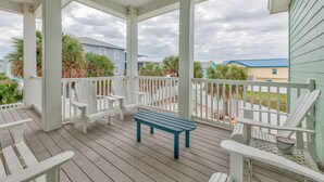 A covered porch with white railings, a blue bench, and white Adirondack chairs. - The Tipsy Turtle features a playroom for little ones, an arcade game room for bi (Port Aransas)