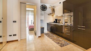 A modern kitchen with a large stove, oven, and cabinets. There is a clock on the wall and a rug on the floor. - Residence Moky D14 - pool, private garden, garage (Lazise)