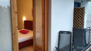 Ein kleines Schlafzimmer mit einem Bett, einem roten Kopfkissen und einer Holztür.