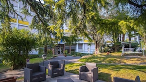 An outdoor seating area with wicker furniture, a paved walkway, and a building in the background.