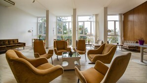 A spacious living room with large windows, a central coffee table, and several armchairs.