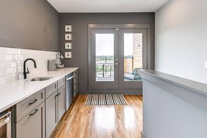 Eine moderne Küche mit einem großen Fenster, einem eingebauten Geschirrspüler und Blick auf den Balkon.