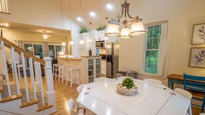 A spacious kitchen with white cabinets, a central island, and pendant lighting. - Beachwalk Resort Charming Main & Guest House (Michigan City)