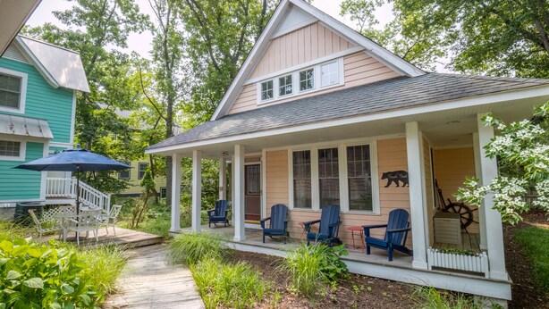 A house with a covered porch, outdoor seating, and a small garden area. - Beachwalk Resort Charming Main & Guest House (Michigan City)