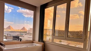 Una habitación de hotel con un ventanal grande, una bañera y una cama.