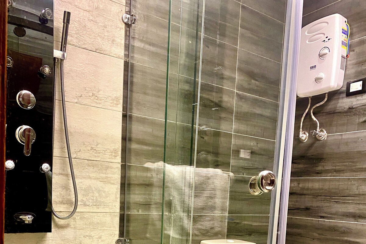 Un baño moderno con ducha de vidrio, inodoro y calentador de agua instalado en la pared.