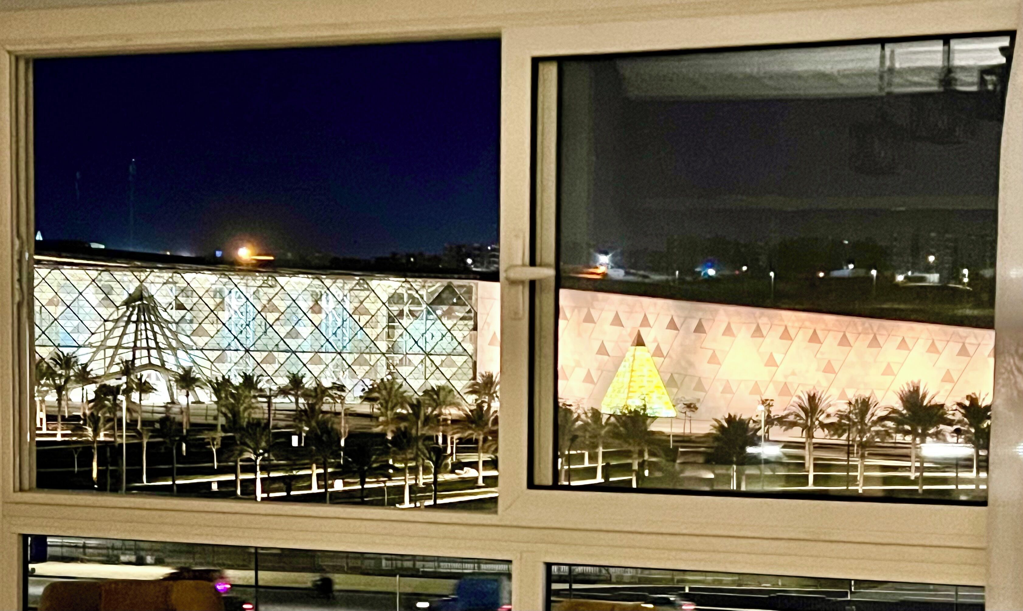 A view of a building with a geometric facade and palm trees.