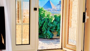 Vista a través de una ventana mostrando las pirámides y un edificio moderno al fondo.