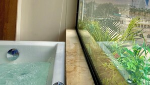 Un baño con bañera y vista panorámica a una ciudad con montañas.
