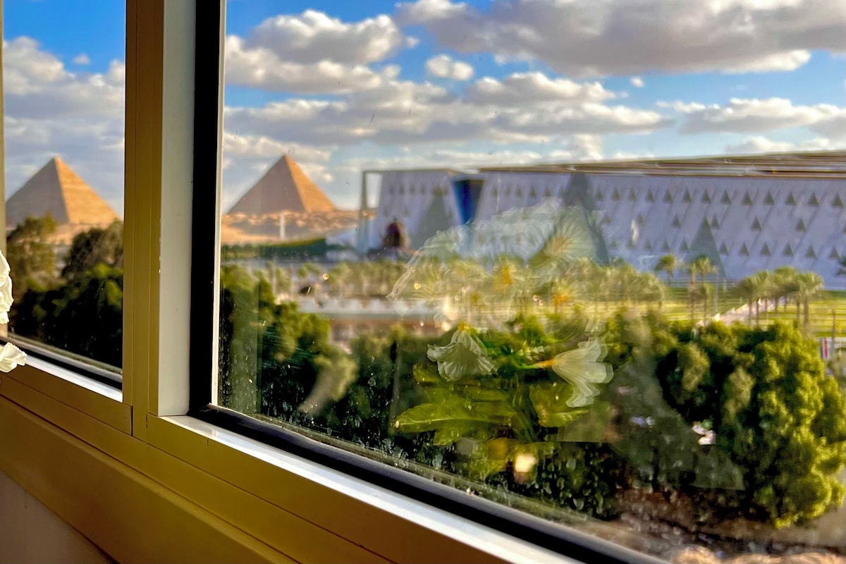 Una ventana con vistas a pirámides y un edificio de fachada decorada.