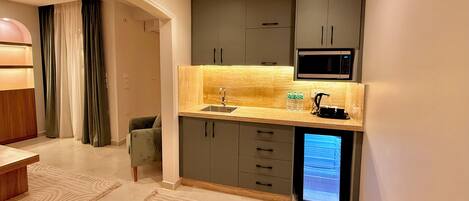 A compact kitchen with a microwave, sink, and a small refrigerator.