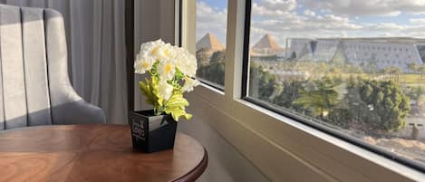 A view from a window with a vase of white flowers on a wooden table.