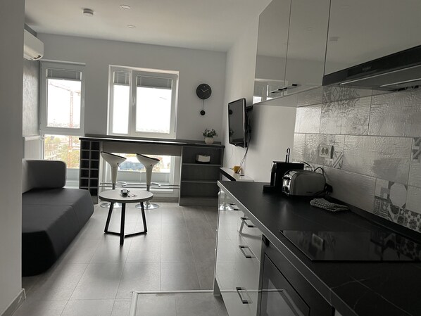 Een moderne keuken met een eethoek, grote ramen en een flatscreen televisie.