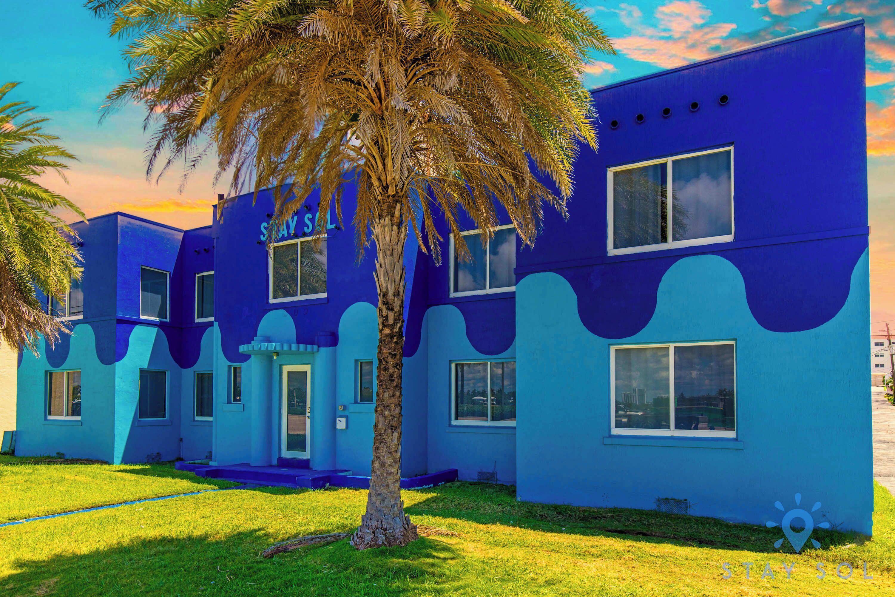 A blue building with the sign "STAY SOL" and a palm tree in front.