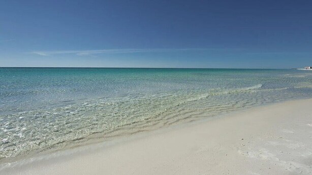A beach with clear turquoise water and a sandy shore.