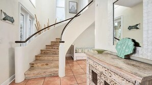 A staircase with wooden steps and a white handrail, leading to a landing with a bench and a decorative wall piece.