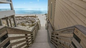 A wooden staircase leading to a beach with a clear view of the ocean.