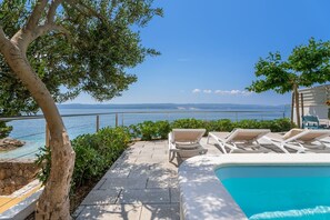 Area piscina con sedie a sdraio e vista sul mare.
