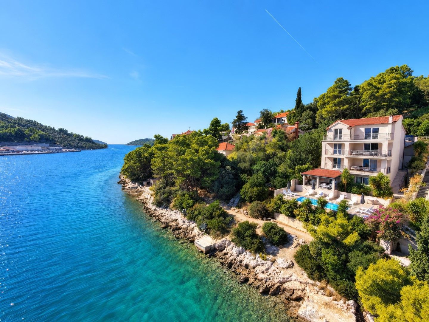A coastal property with a swimming pool, multiple balconies, and a view of the sea.
