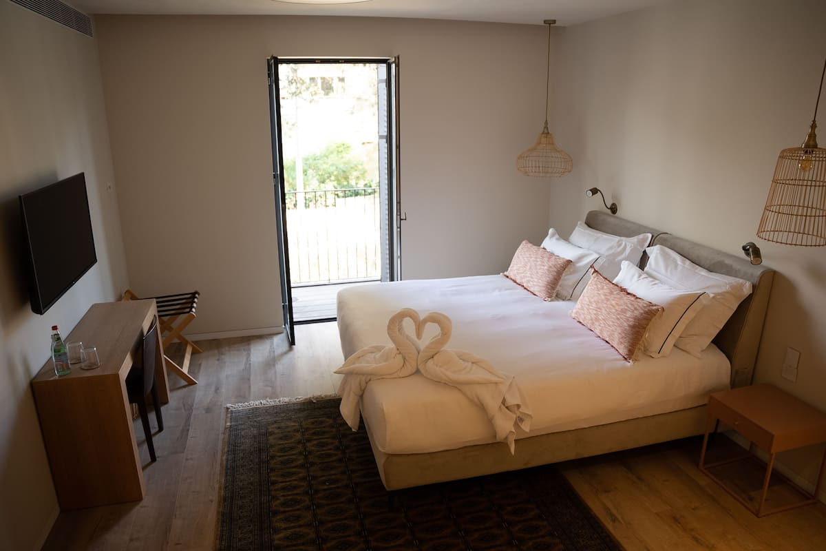 A hotel room with a bed, a desk, a television, and a sliding door to the outside.
