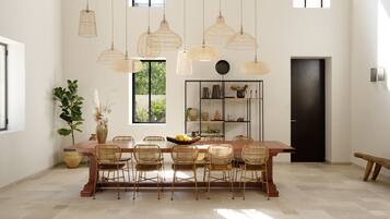 A dining area with a wooden table, wicker chairs, and hanging light fixtures.