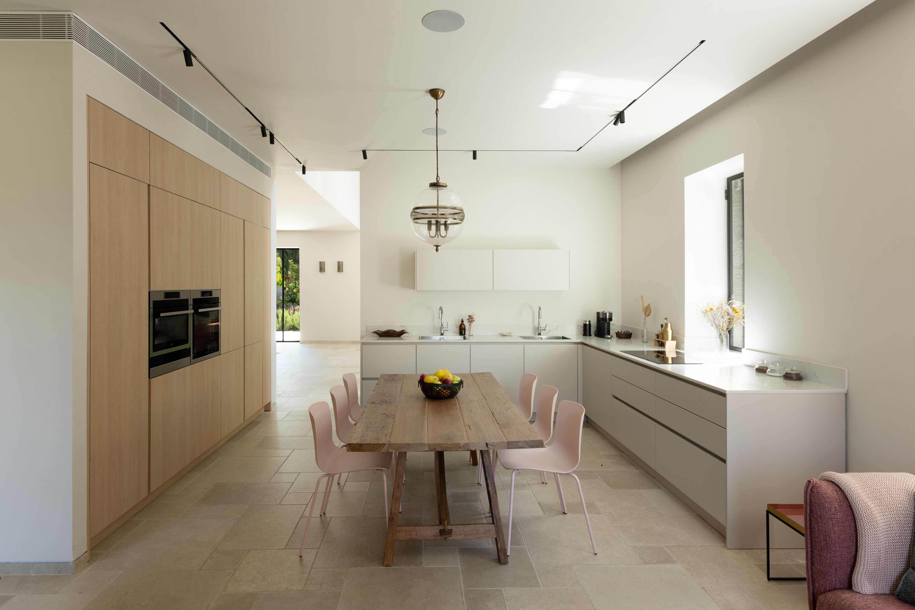 Een moderne keuken met een houten eettafel, witte kasten en een groot keukeneiland met een spoelbak.