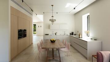 Een moderne keuken met een houten eettafel, witte kasten en een groot keukeneiland met een spoelbak.