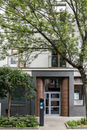 Um edifício moderno com entrada de vidro, placa de estacionamento e painel com texto.