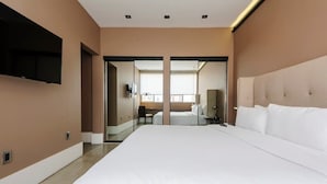 Een moderne hotelkamer met een groot bed, een flatscreen televisie aan de muur en een schuifdeur naar een badkamer.