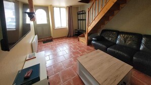 A living room with a wooden staircase, a black leather sofa, and a wooden coffee table. - Maison Entière Avec Cour Intérieure (Monthureux-sur-Saône)