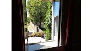 A window with a view of a garden and a pathway. - Maison Entière Avec Cour Intérieure (Monthureux-sur-Saône)