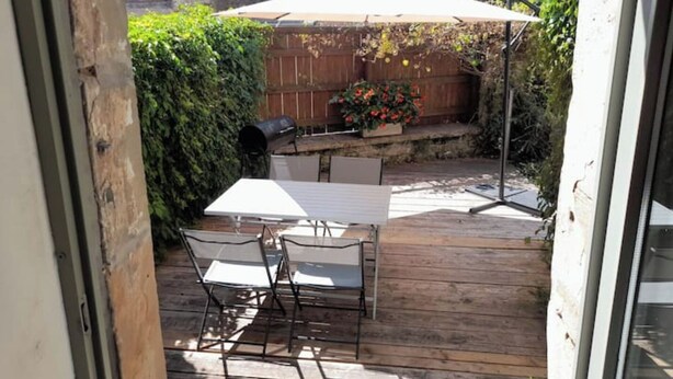 A patio with a table and chairs, a barbecue grill, and a wooden fence. - Maison Entière Avec Cour Intérieure (Monthureux-sur-Saône)