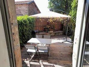A patio with a table and chairs, a barbecue grill, and a wooden fence. - Maison Entière Avec Cour Intérieure (Monthureux-sur-Saône)