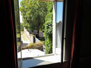 A window with a view of a garden and a pathway. - Maison Entière Avec Cour Intérieure (Monthureux-sur-Saône)
