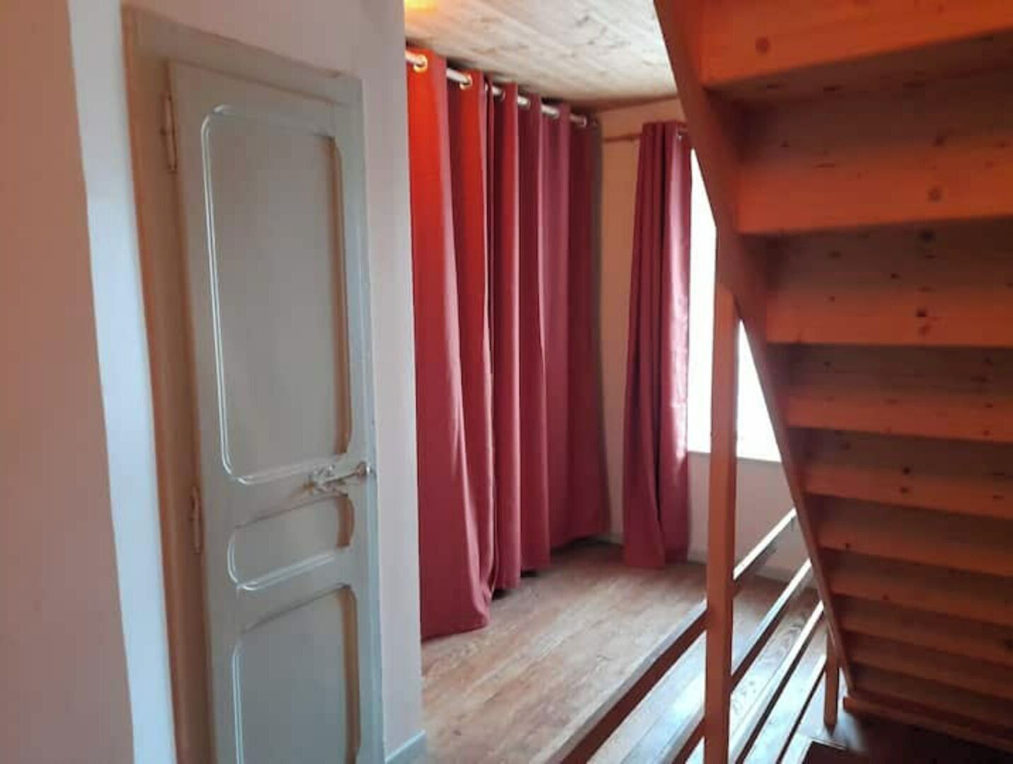 Una escalera que lleva a una habitación con piso de madera y una puerta con marco blanco.