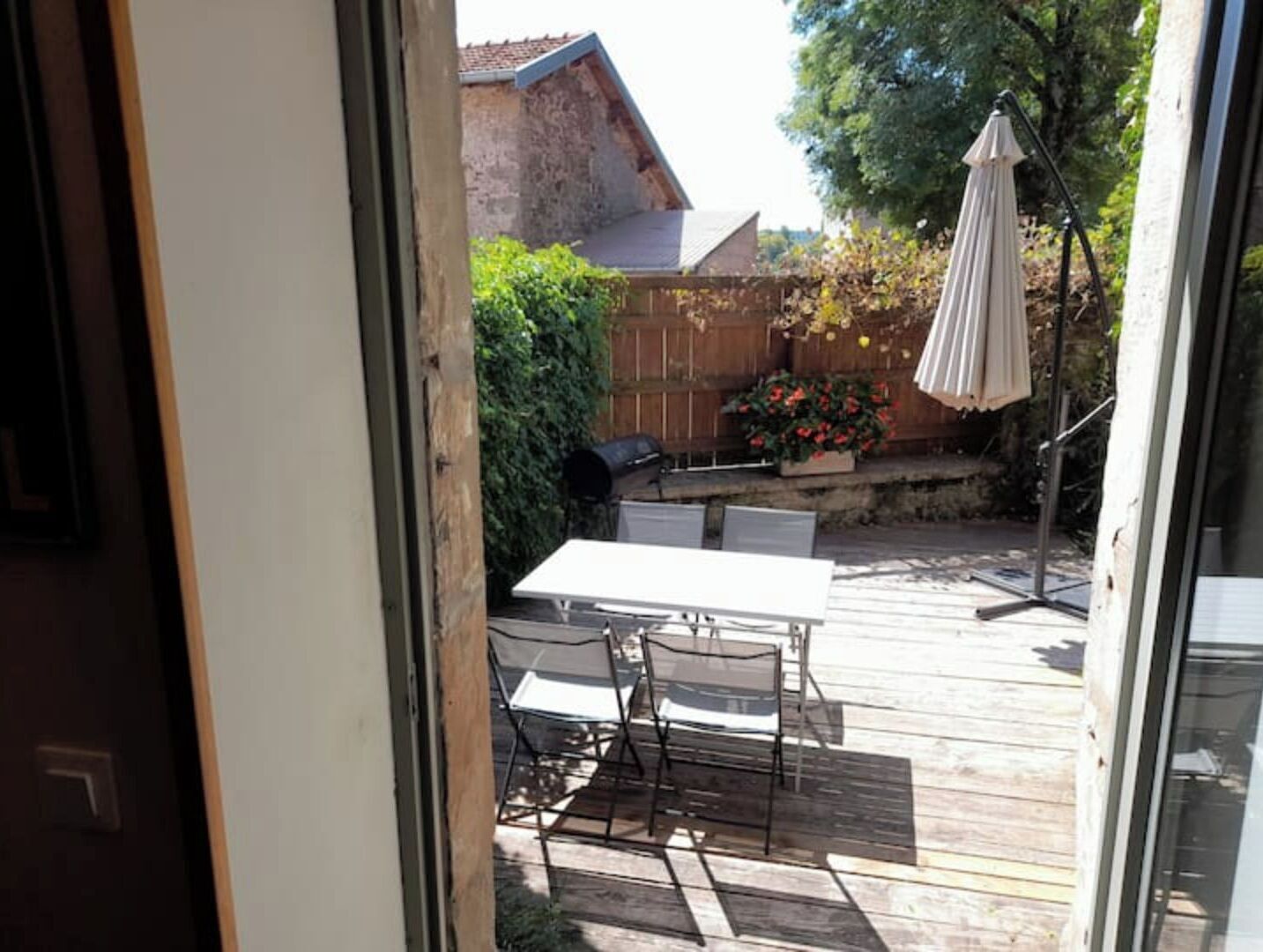 A wooden deck with a table and chairs, a barbecue grill, and a patio umbrella.