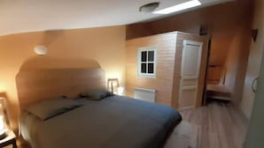 A bedroom with a bed, a nightstand, a window, and a door. - Maison Entière Avec Cour Intérieure (Monthureux-sur-Saône)